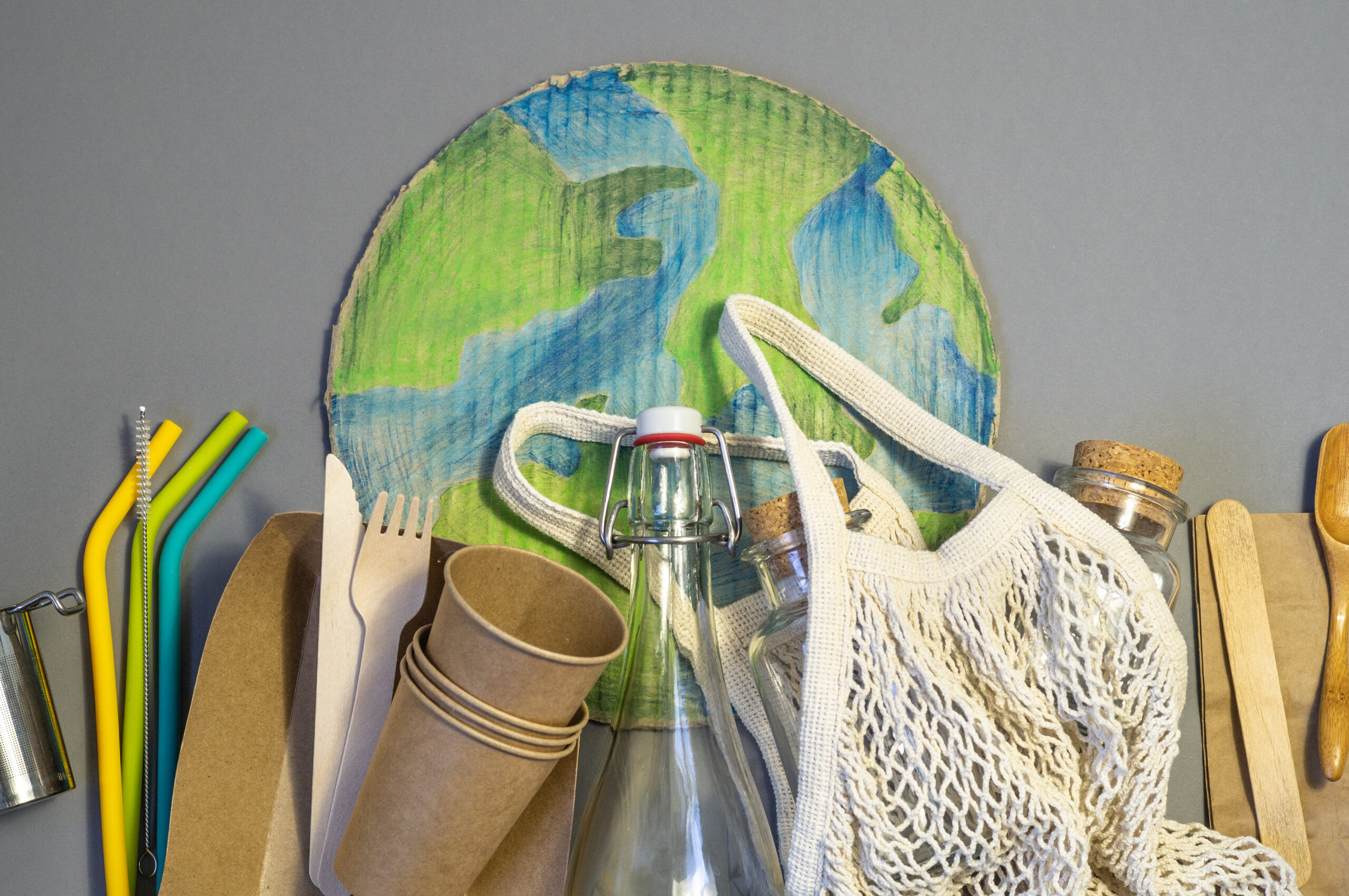 Zero waste concept. String bag, glass jars and silicone drinking straw on grey background. Eco friendly and reuse concept