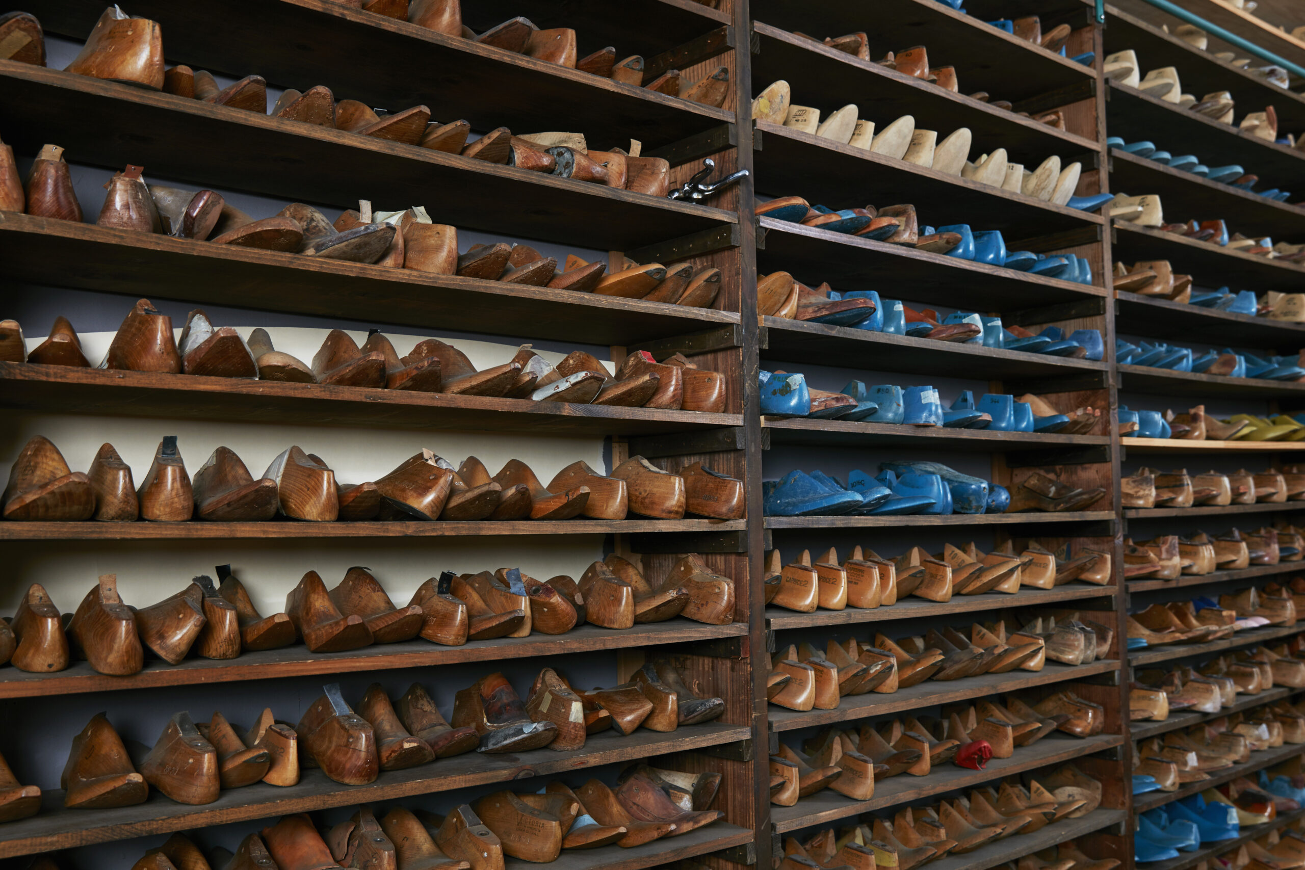 Rows of old wooden shoe lasts on shelves in traditional shoe shop