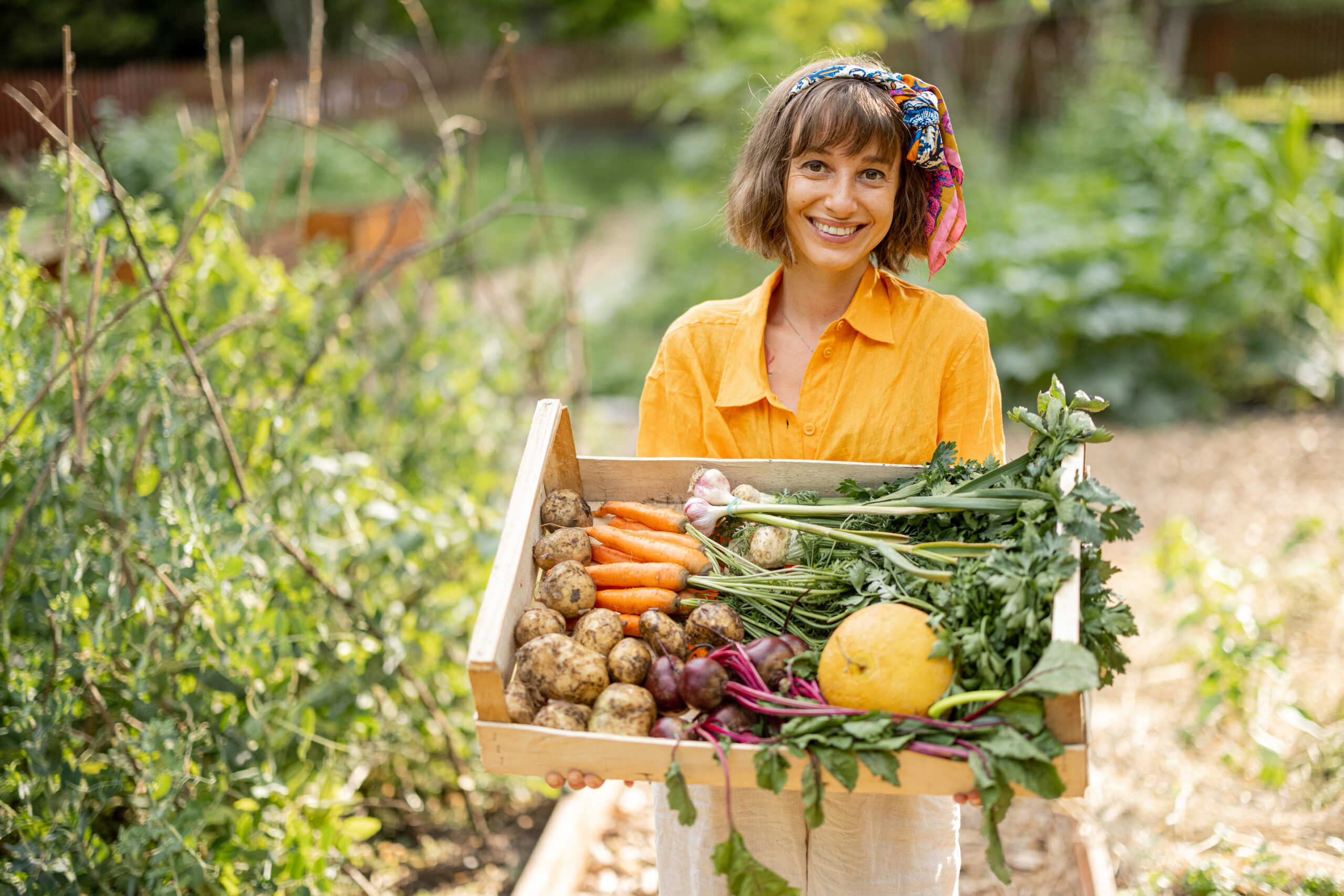 Young farmer with freshly picked vegetables at garden